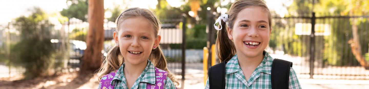 two students with big smiles walking to school