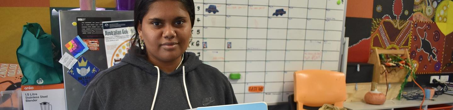 Ernabella Aṉangu School student Kellis Dare Lawrie holding the book she illustrated.