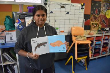 Ernabella Aṉangu School student Kellis Dare Lawrie holding the book she illustrated.