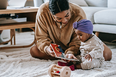 A baby and parent reading a picture book together.