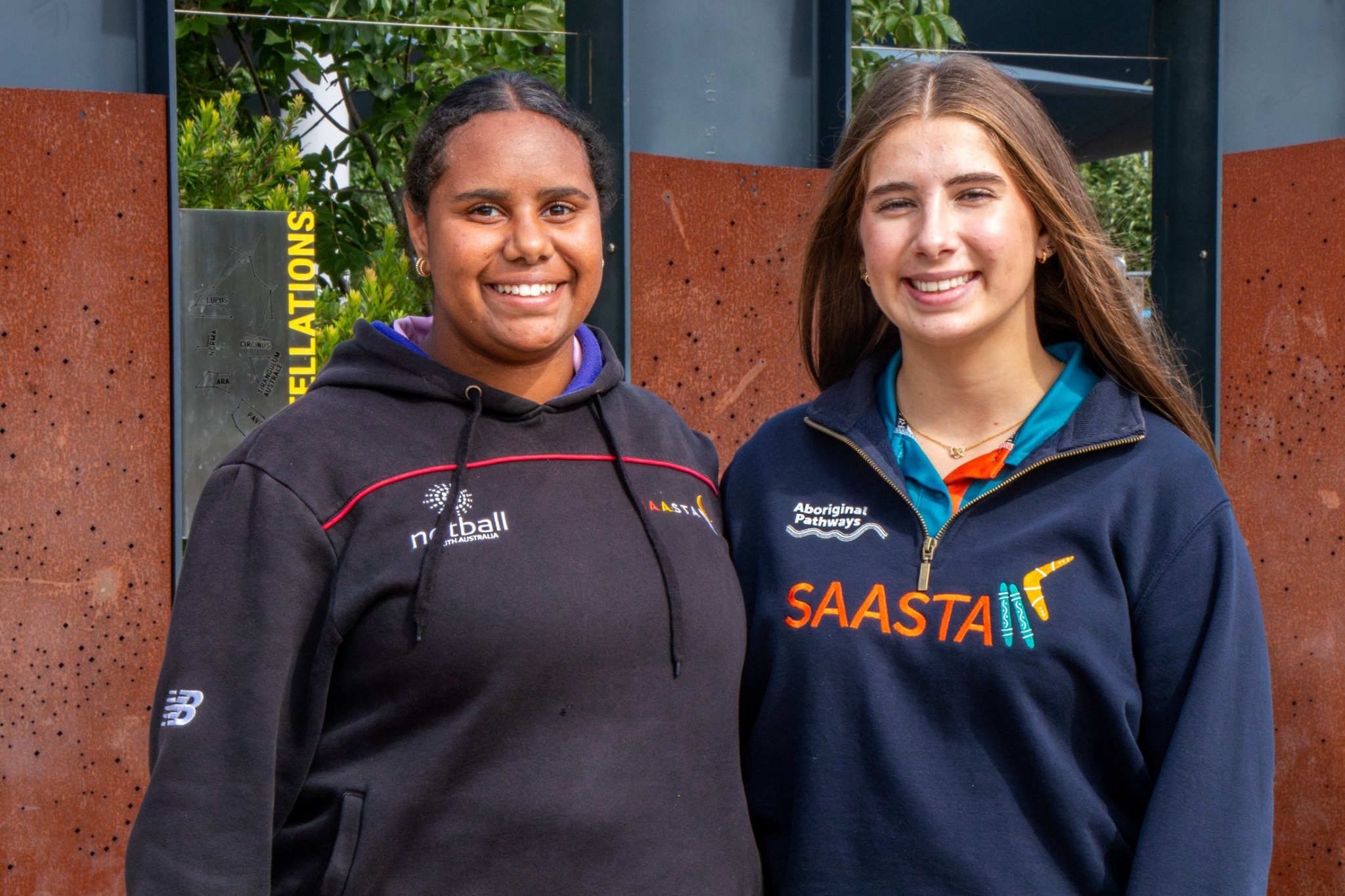 Two Aboriginal Pathways students standing together outdoors and smiling at the camera.