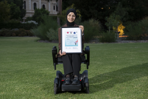 A group of people standing on grass, each holding a framed certificate.