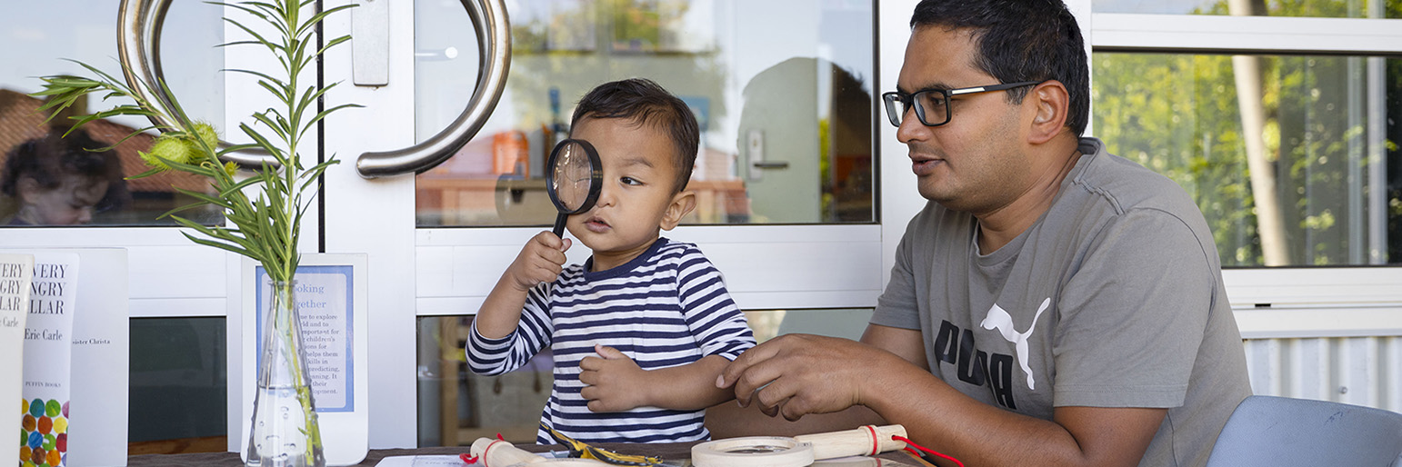 A parent and child looking at a table of shells together