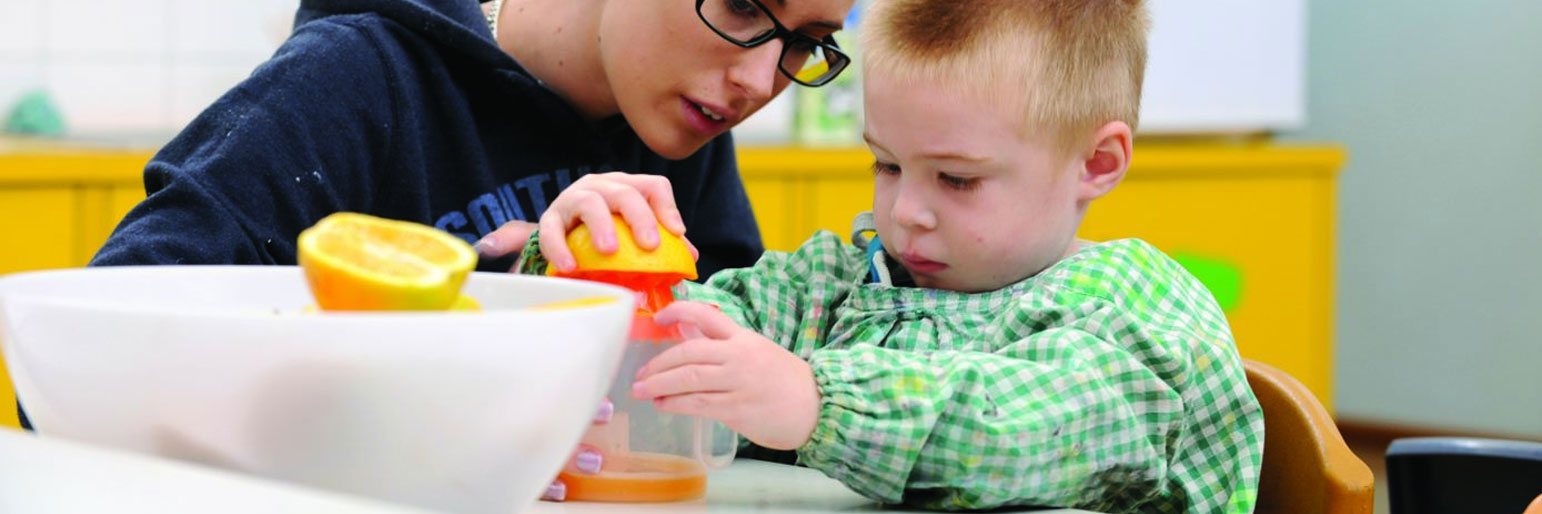 A parent and child squeezing orange juice together