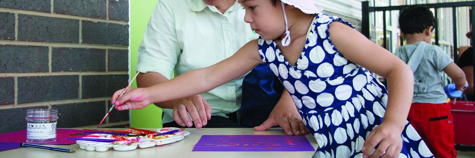 A parent watching a child paint a sign