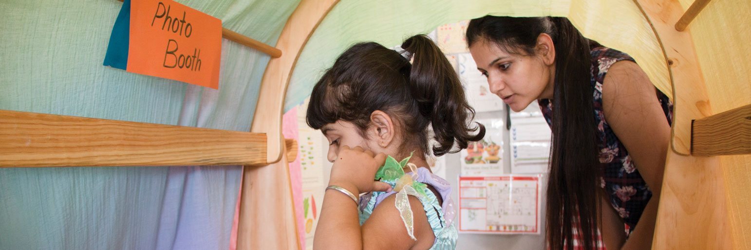 A child dressing up in costumes while their mother watches